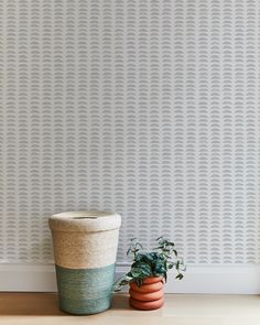 a potted plant sitting next to a wallpapered wall with an interesting pattern