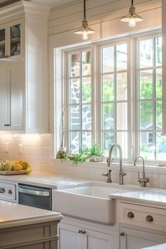 a kitchen filled with lots of white cabinets and counter top space next to a window