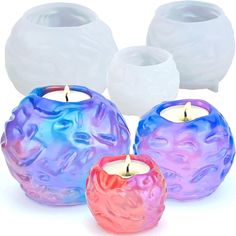 three colorful candles sitting next to each other on a white surface with one candle in the middle