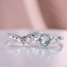 a ring with an aquamarine colored stone and white diamonds on the side, sitting on top of a table