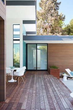 an outdoor deck with chairs and tables next to a door that leads into the backyard