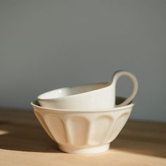 two white bowls sitting on top of a wooden table