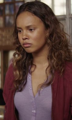 a woman with long curly hair is looking at the camera and has an angry look on her face