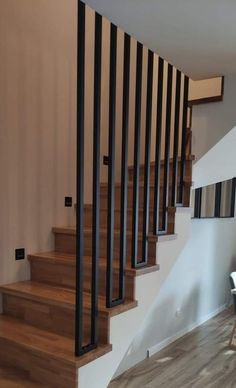 there is a wooden stair case next to the table and chair in this room with white walls