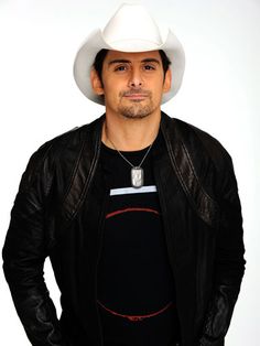 a man wearing a white cowboy hat and black shirt with his hands in his pockets