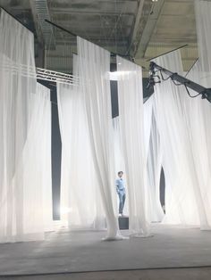 a person standing in front of white curtains