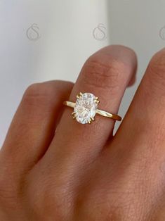 a woman's hand with a diamond ring on top of her finger, showing the center stone