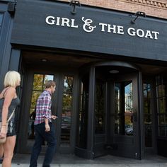 two people are walking out of the door of a restaurant that says girl and the goat