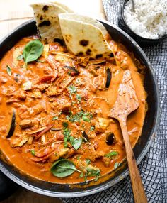 a skillet filled with red curry and tortilla chips