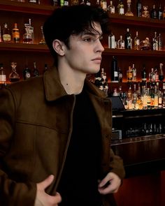 a man standing in front of a bar filled with liquor bottles