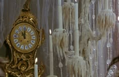 an ornate gold clock surrounded by candles and chandeliers