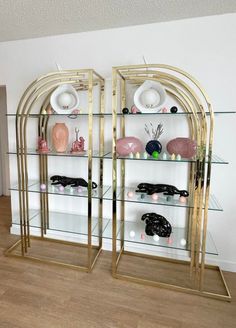 two glass shelves with vases and other items on them in the corner of a room