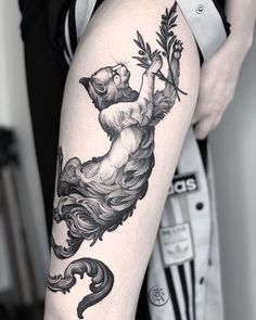 a woman's leg with a bear and flower tattoo design on it, in black and white