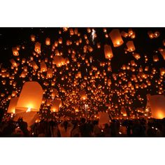 many people are flying lanterns in the dark