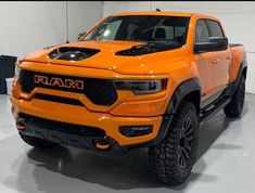 an orange ram truck is parked in a room with white walls and black trims