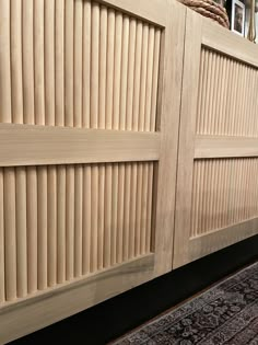 a close up of a wooden door on a wall with a rug in front of it