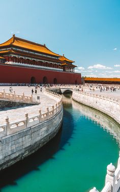 people are walking around in front of the forbidden city wall and water canal, which is surrounded by white stone walls