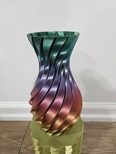 a multicolored vase sitting on top of a wooden floor next to a wall