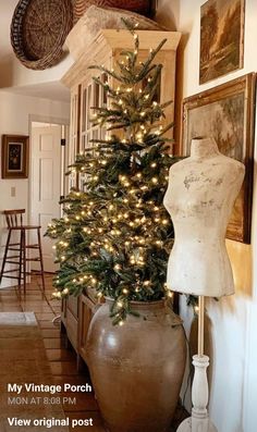 a small christmas tree in a vase next to a mannequin on the wall