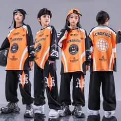 three young boys in orange and black outfits standing next to each other with their hands on their hips