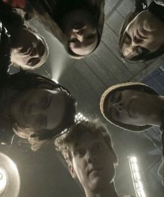 a group of people standing in a circle looking up at the camera with their eyes closed