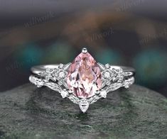 an engagement ring with a pink diamond in the center on top of a stone slab