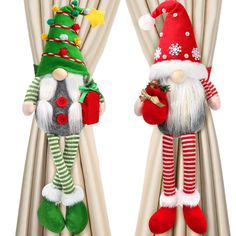 two christmas decorations hanging from the side of curtains with santa hats and stockings on them