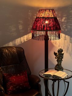 a lamp sitting on top of a table next to a brown chair and a book