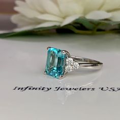 Paraiba Tourmaline Ring, Emerald Cut Engagement Ring 14K Gold, Three Stone Ring, Paraiba Ring For Ladies, Art Deco Paraiba Ring, #6311 This ring is an emerald cut lab created neon blue paraiba with round moissanite sides, 14k white gold # 6311 We feature the finest quality of lab grown stones in the world. The properties of lab-grown are physically, chemically and visually identical to natural, just grown in a lab setting. -Approximate total carat weight: 3.85ctw. diamond equivalent -Center Ston Gia Certified Tourmaline Rings For Formal Occasions, Gia Certified Radiant Cut Sapphire Ring Gift, Tourmaline Ring With Prong Setting For Anniversary, Emerald Cut Tourmaline Ring For Anniversary, Tourmaline Prong Setting Anniversary Ring, Tourmaline Rings With Prong Setting For Anniversary, Gia Certified Oval Topaz Ring For Gift, Fine Jewelry Tourmaline Rings With Brilliant Cut, Gia Certified Baguette Cut Topaz Ring Gift