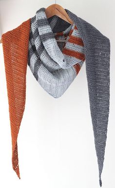 two scarves hanging from a hook on a white wall next to a coat rack