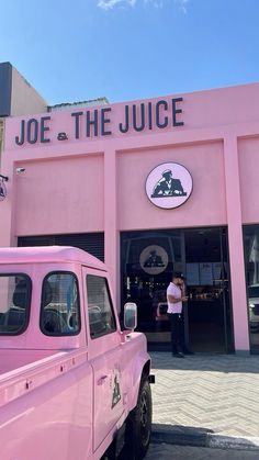 a pink truck parked in front of a building with the words joe and the juice on it