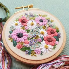 a close up of a embroidery on a table next to some yarn and threads