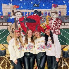 four girls are posing in front of a mural