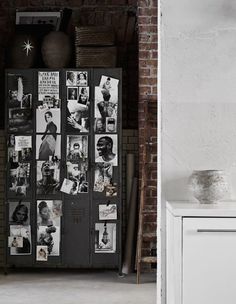 a cabinet with pictures on it next to a brick wall