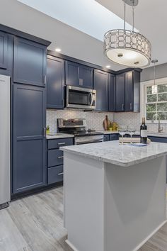 a large kitchen with blue cabinets and white counter tops, an island in the middle