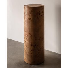 a large round wooden table sitting on top of a cement floor next to a white wall