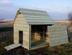 a dog house made out of wood in the grass