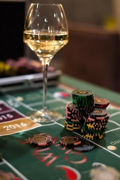 a glass of wine and some casino chips on a table