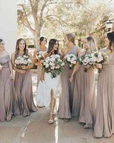 a group of women standing next to each other wearing dresses and holding bouquets in their hands