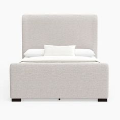 an upholstered bed with two pillows on the headboard and one pillow on the foot board