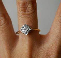 a woman's hand with a diamond ring on top of her finger, showing the center stone