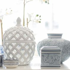 white vases and other decorative items sit on a shelf in front of a window