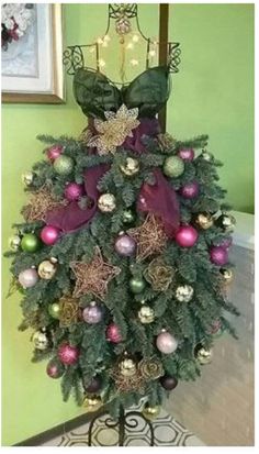 a christmas tree with purple and green ornaments on it's top, in front of a mirror