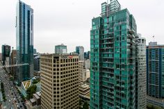 an aerial view of some very tall buildings in the city with cars driving down the street