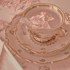 a tea cup and saucer sitting on top of a table covered in pink flowers