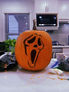 a carved pumpkin with a ghost face on it's side and mouth open in front of a kitchen counter