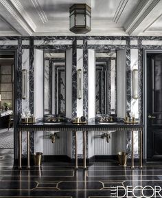 the bathroom is decorated in black and white marble with gold accents on the walls, along with two sinks