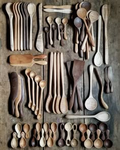 many wooden spoons are lined up on a table with different shapes and sizes in them