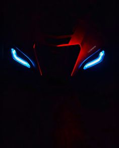 the headlights of a sports car are glowing red, blue and white in the dark