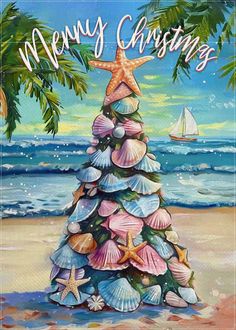 a christmas tree made out of seashells on the beach with a sailboat in the background